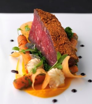 Plate with carrots, carrot curls and puree with a beef cut with a spice crust and balsamic dots
